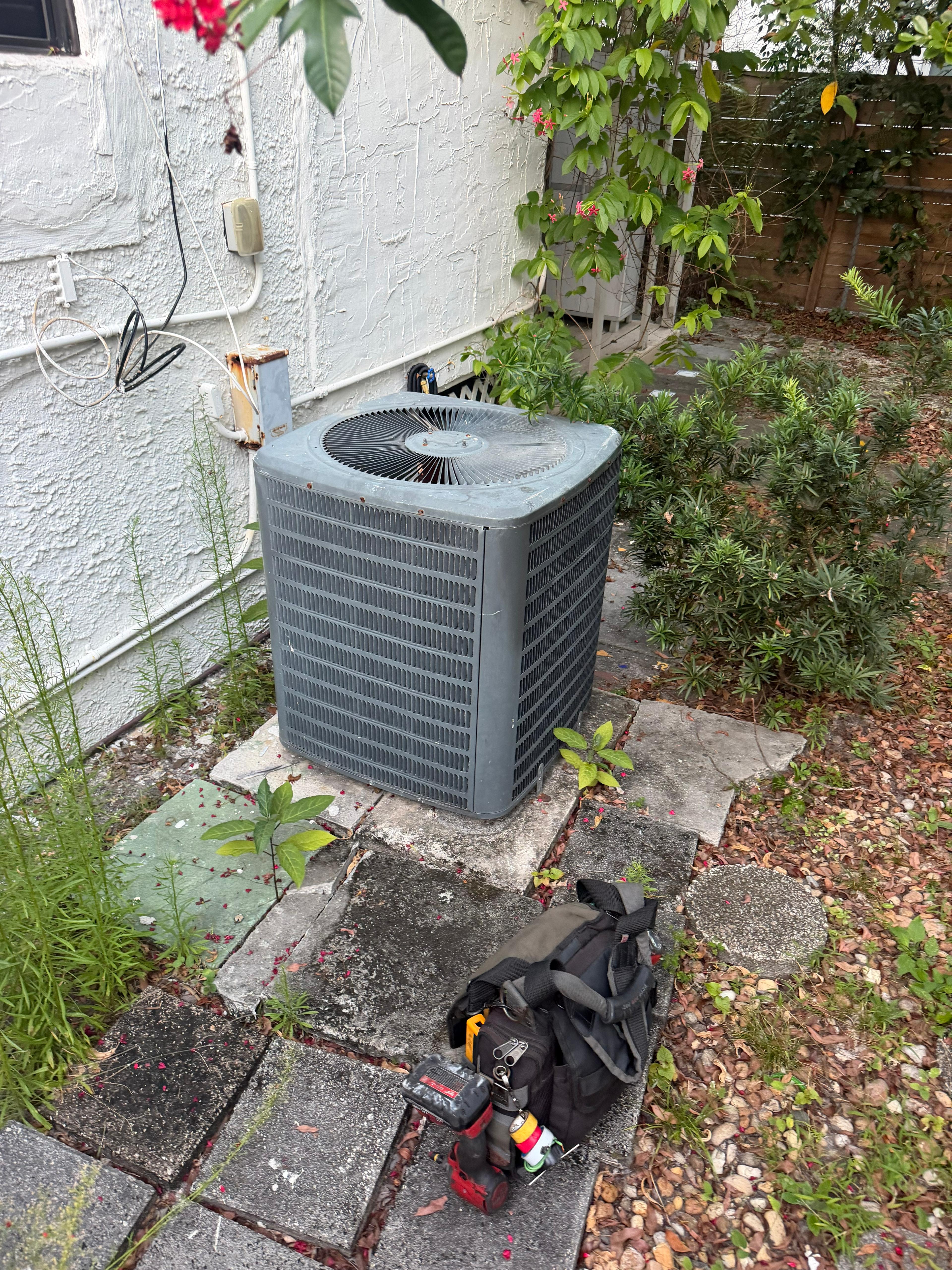 Condenser unit with Cooling Masters tool bag — residential AC service call
