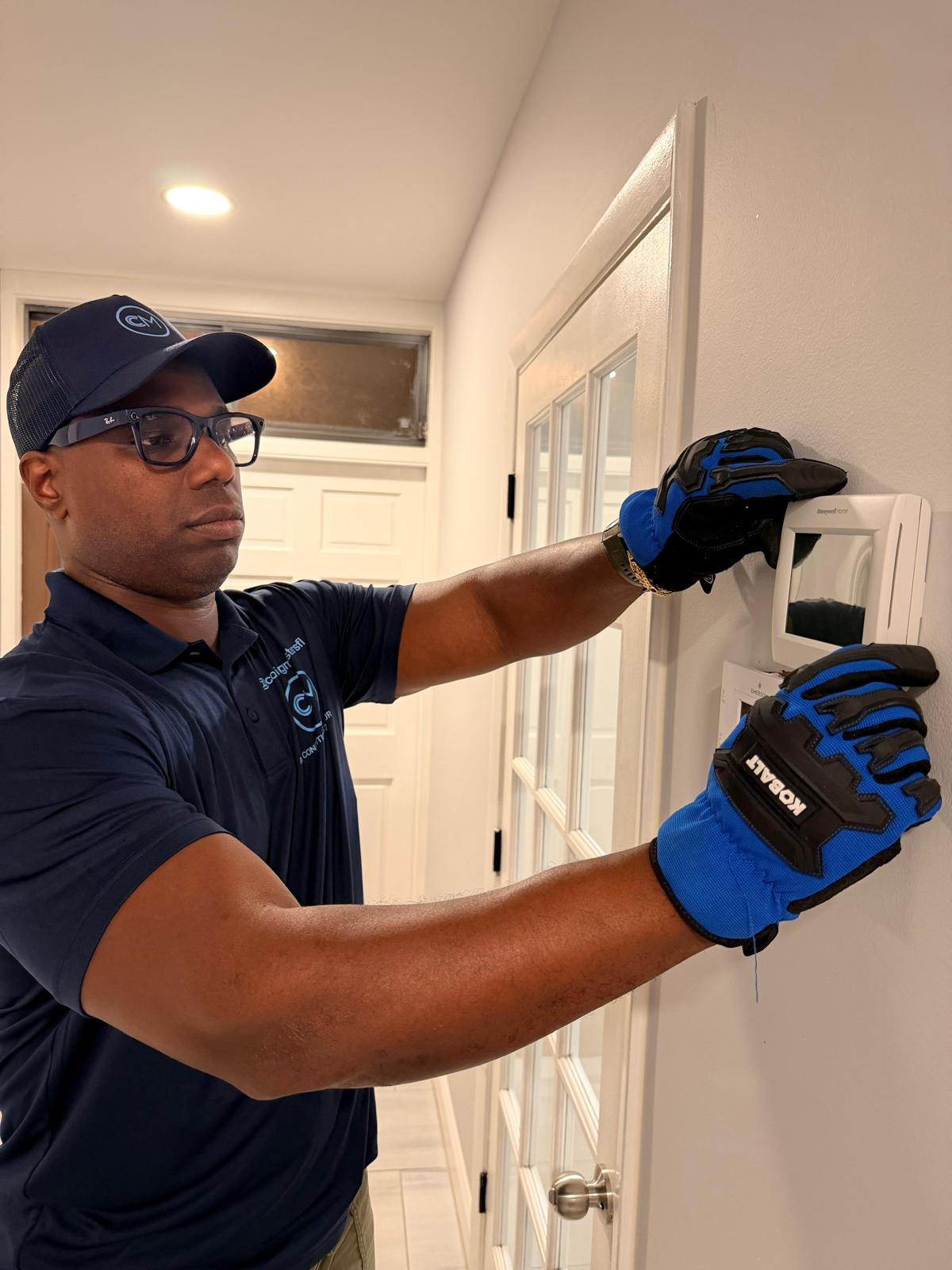 Cooling Masters certified technician installing a smart thermostat in a Coconut Grove home